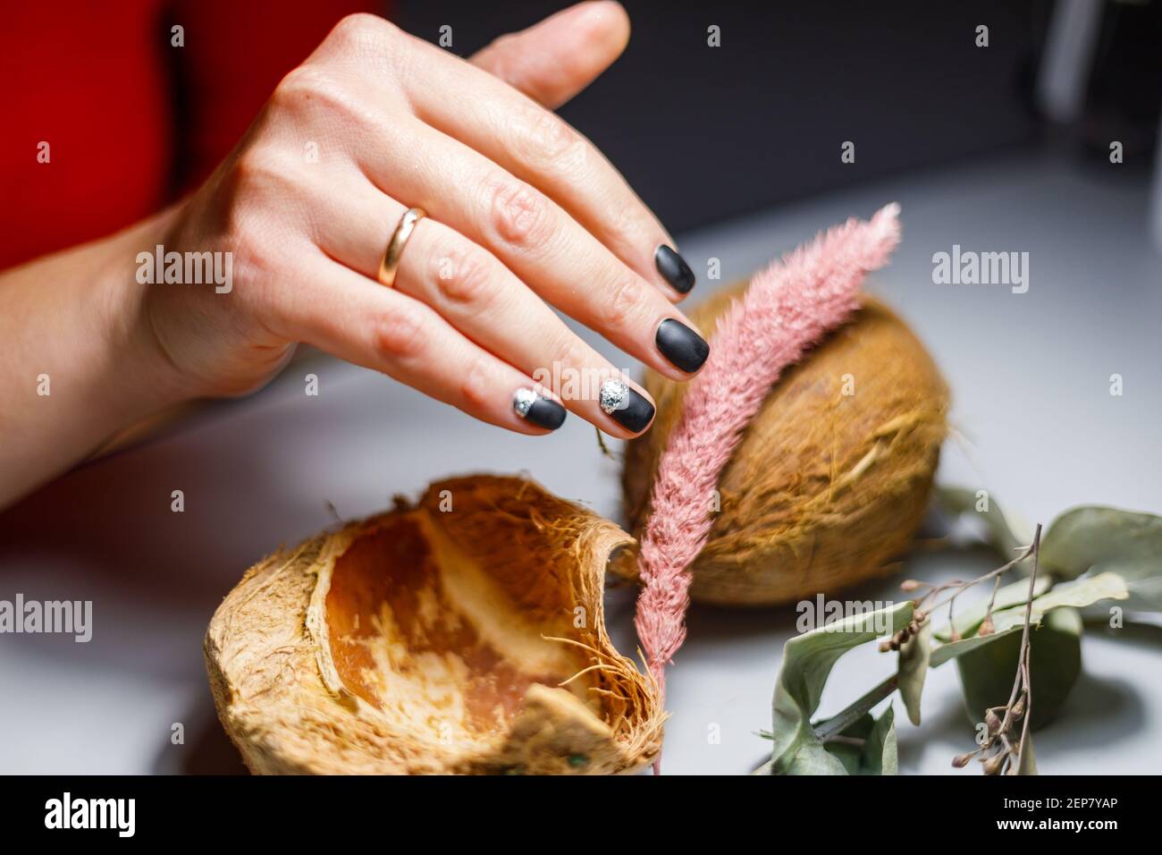 In einem Schönheitssalon macht der Meister eine Maniküre, trägt ein Muster auf den Nagel mit einem Pinsel, schwarzer Lack mit einem goldenen Muster. Stockfoto