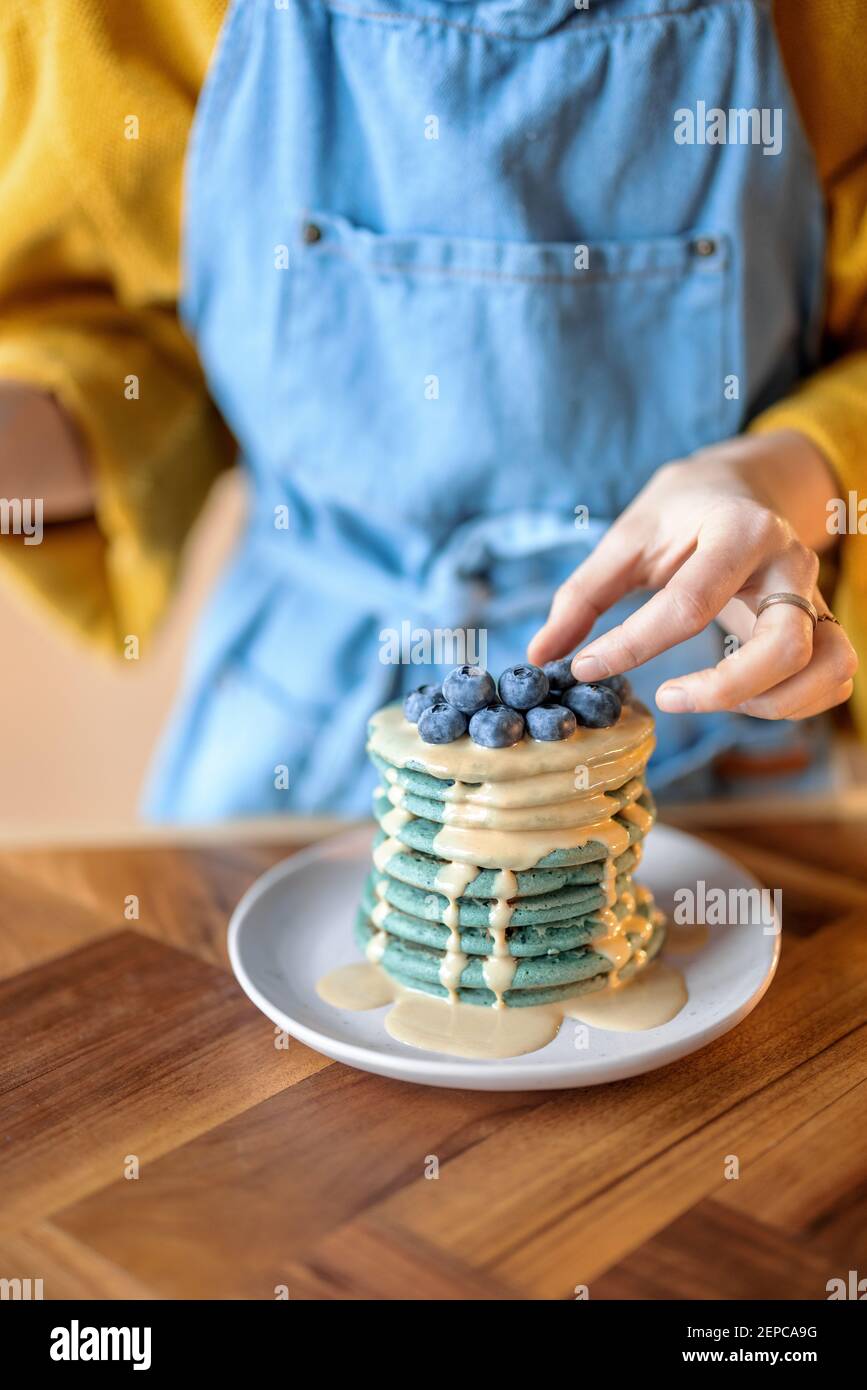 Frau schmücken blaue Pfannkuchen mit Heidelbeere. Stockfoto