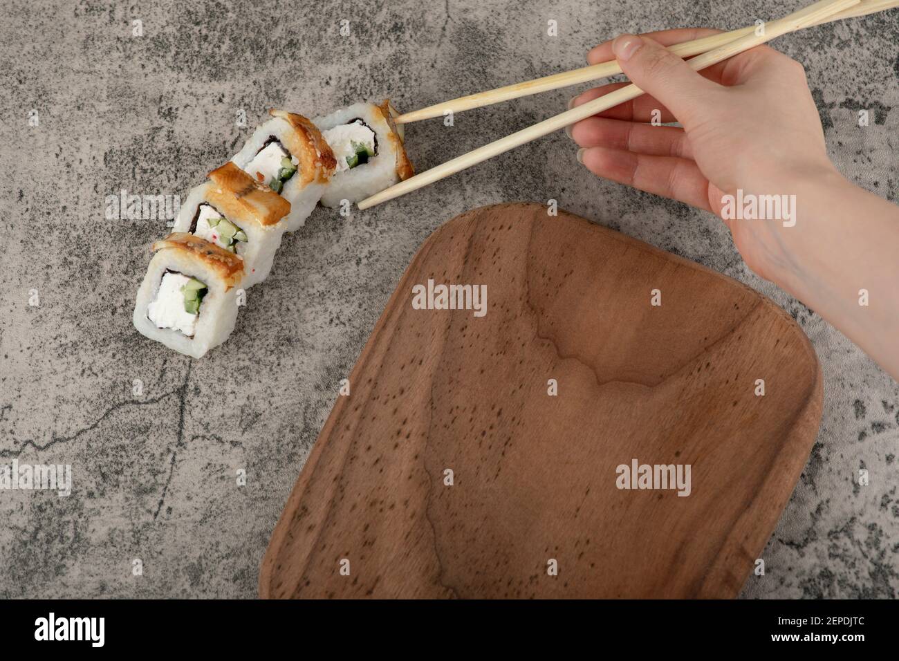 Frau Hand Kommissionierung panierte Sushi-Rolle mit Essstäbchen Stockfoto