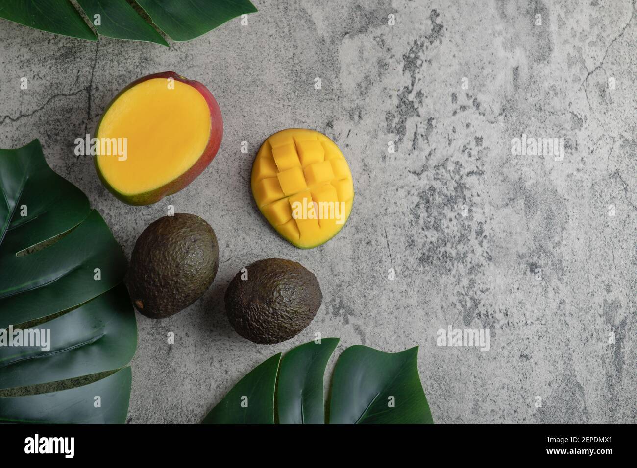 Geschnittene Mango und reife Avocado-Früchte auf Marmoroberfläche Stockfoto