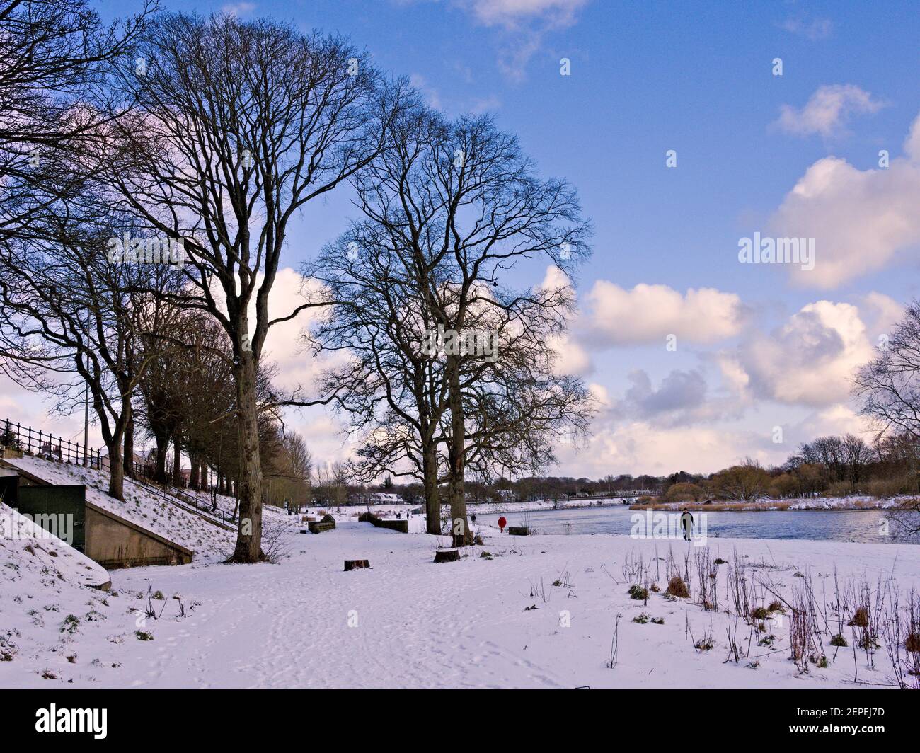 Walker am Ufer des Flusses Dee im Winterschnee Stockfoto