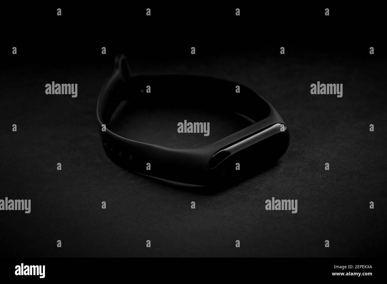 Schwarze elektronische Uhr und Smart Fitness Tracker auf texturiertem schwarzem Hintergrund. Dunkles Objekt auf dunklem Hintergrund. Dunkle Luxus-Stimmung. Stockfoto