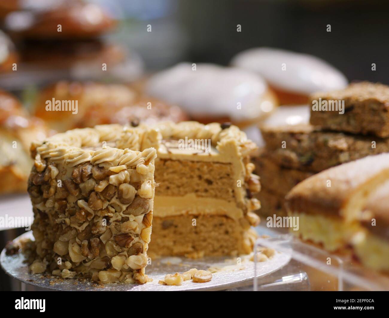 Auswahl an frischen Kuchen, Kaffee und Walnusskuchen, Victoria Sponge Kuchen, Eistüten, Flapjacks und Gebäck zum Verkauf im Coffee Shop Stockfoto