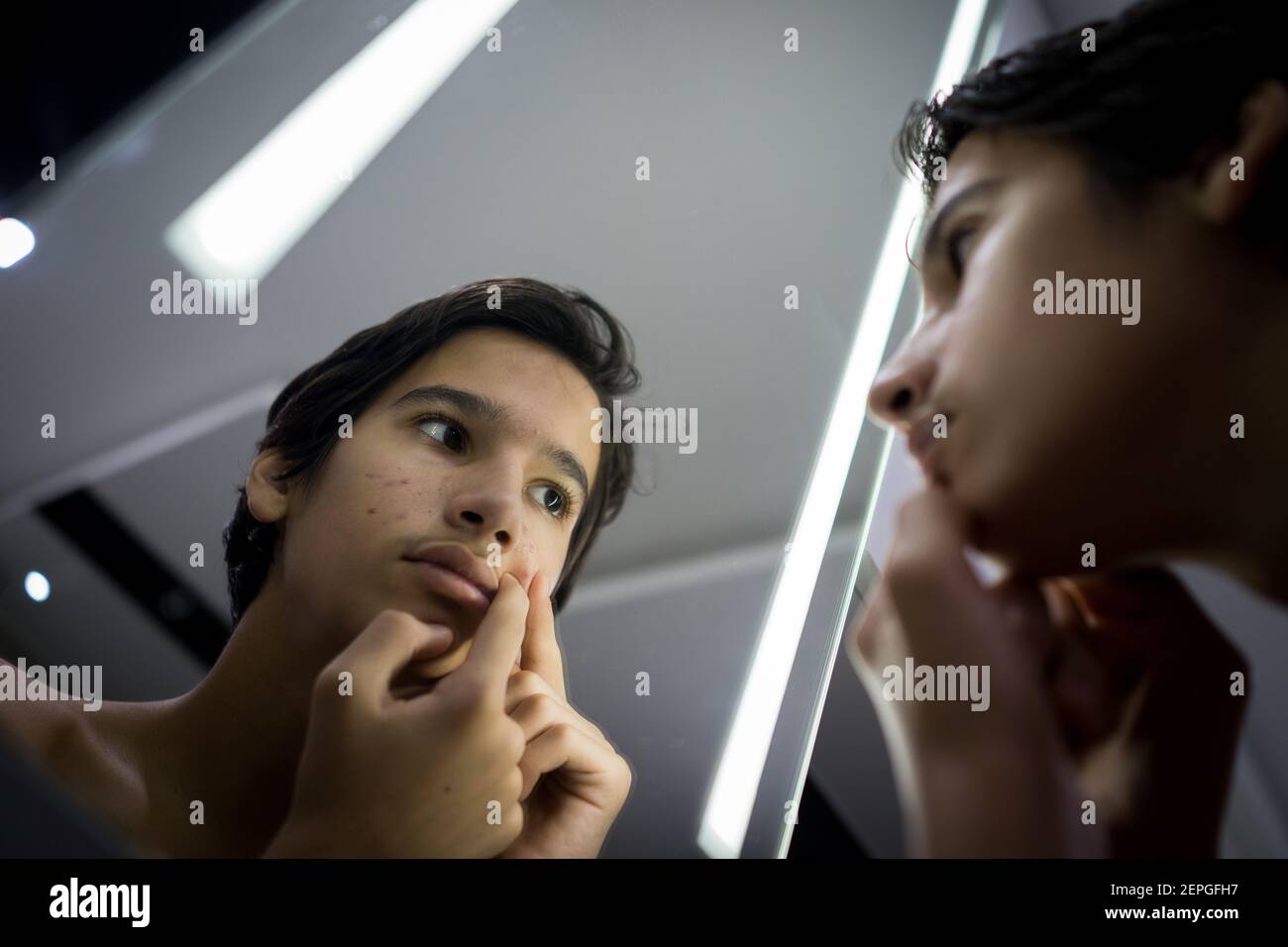 Teenager Junge überprüft seine Haut im Spiegel Stockfoto