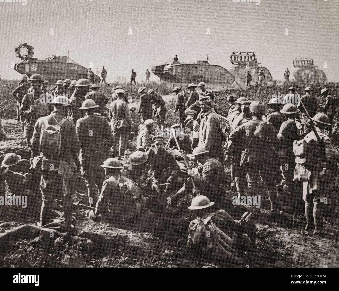 Männer der amerikanischen 30th Division in Ruhe mit deutschen Gefangenen nach der Gefangennahme von Bellicourt, 29. September 1918. Im Hintergrund sind britische Mark V Panzer (mit "Krippen" für die Überquerung von Schützengräben) des Bataillons 8th, Tank Corps, das eines von vier Bataillons der 5th Tank Brigade war, die der 5th Australian Division und American Corps für die Operation zugeteilt wurden. Stockfoto