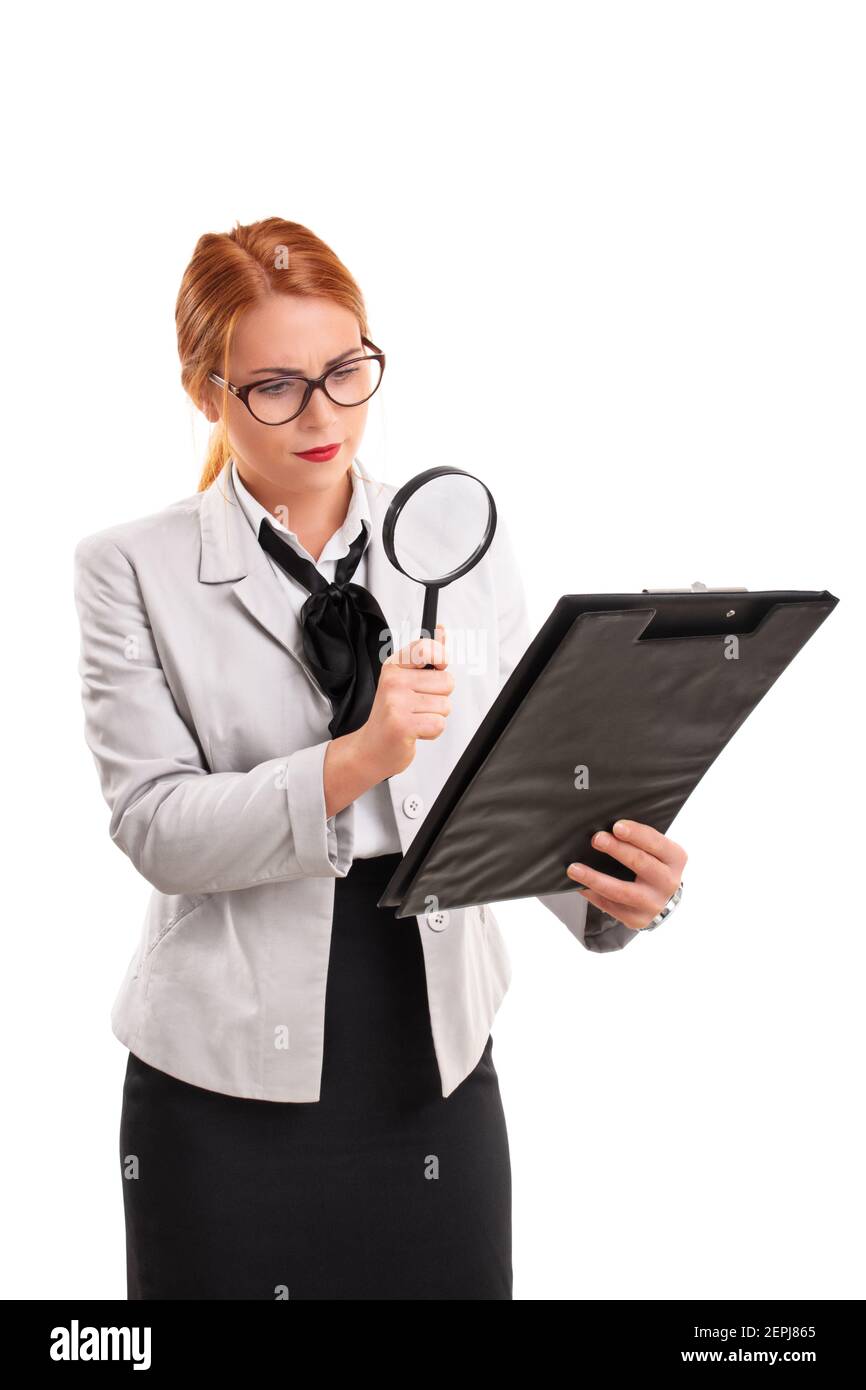 Ein Porträt einer jungen Geschäftsfrau, die ein Dokument auf einer Zwischenablage durch eine Lupe betrachtet, isoliert auf weißem Hintergrund. Stockfoto
