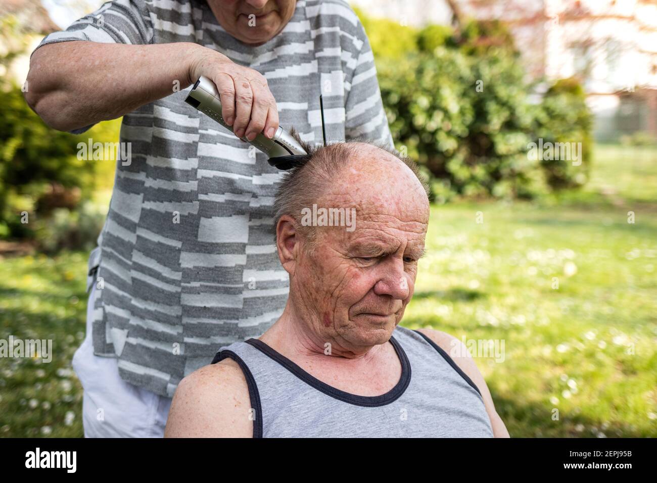 Frau macht Haarschnitt mit Haarschneider zu älteren Mann im Freien im  Garten. Ältere Menschen kümmern sich gegenseitig. Seniorenpaar  Stockfotografie - Alamy