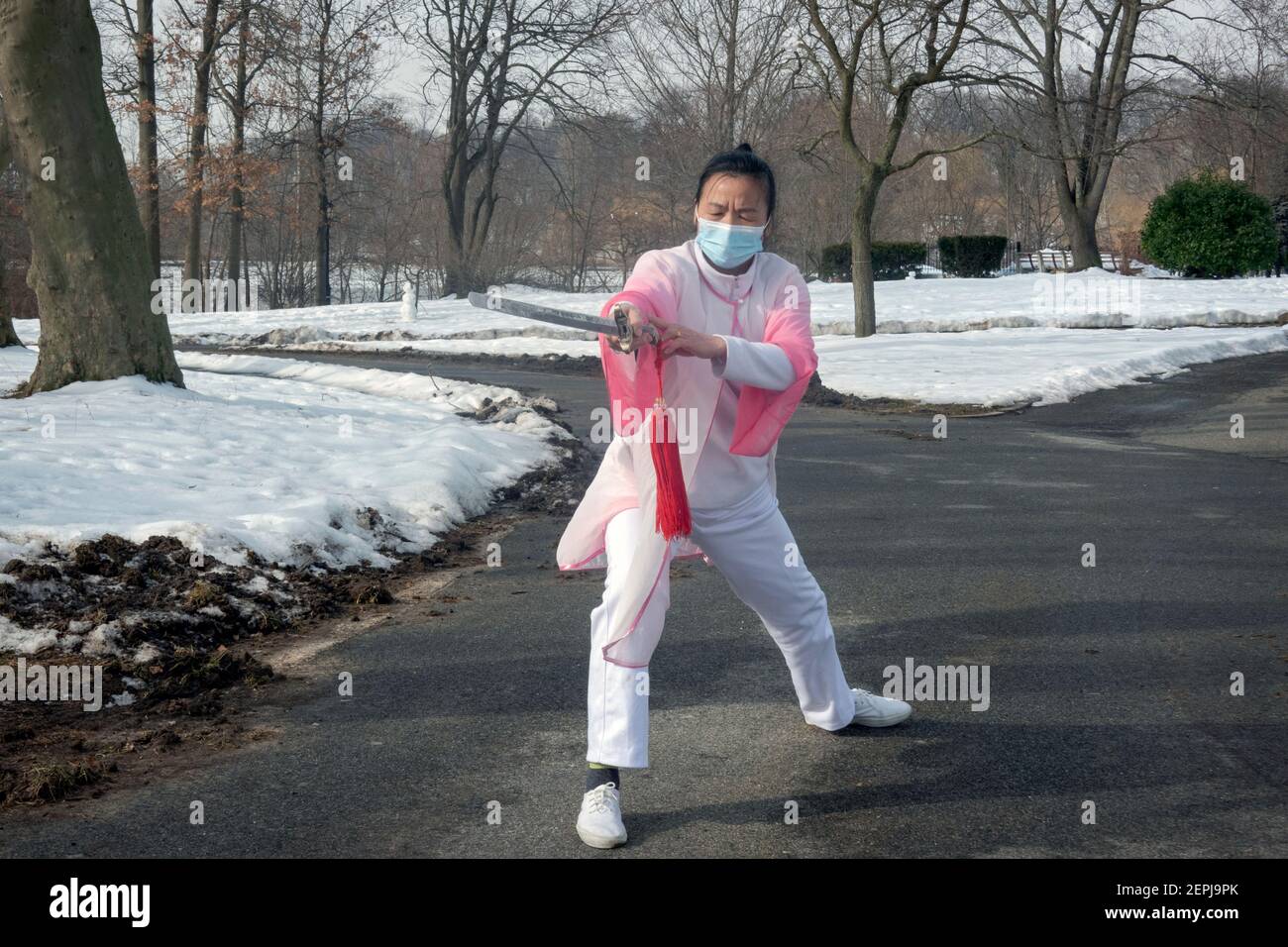 Eine chinesische Amerikanerin mittleren Alters macht anmutig Tai Chi-Tanzübungen mit einem Schwert in einem Park in Flushing, Queens, New York City. Stockfoto