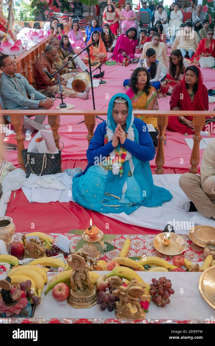 Ein Hindu devotee feiert ihren 70. Geburtstag durch das Sitzen auf dem Altar und der Unterstützung in der Morgen. In Jamaica, Queens, New York City. Stockfoto