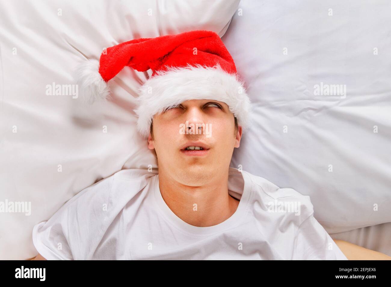 Sehr müde junger Mann in Santa hat schlafen in der Bett im Haus Stockfoto