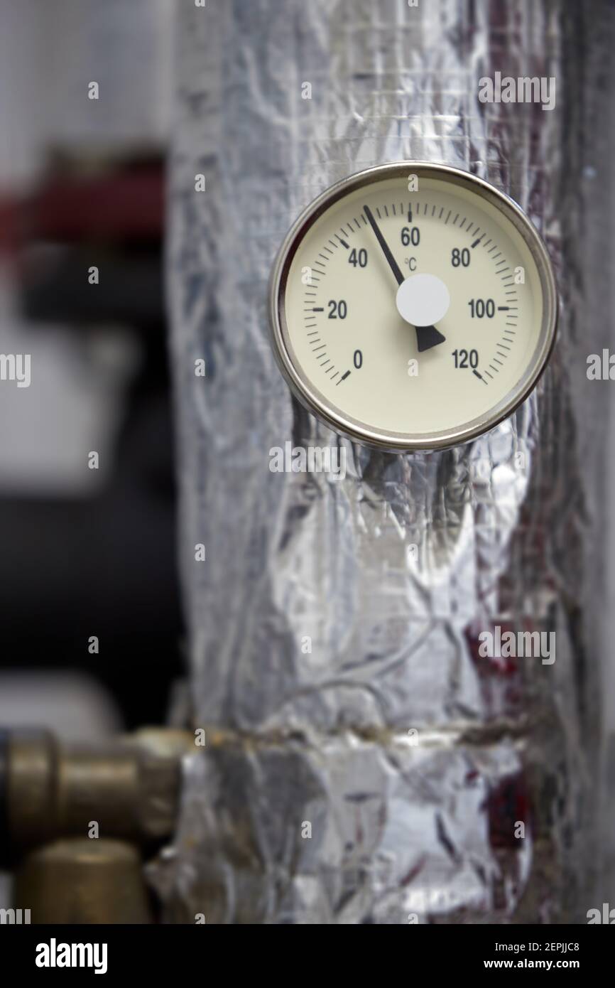 Zentralheizung. Thermometer an der Warmwasserzuleitung zum Heizsystem.  Techniker trägt rote Jacke mit weißem Helm Stockfotografie - Alamy