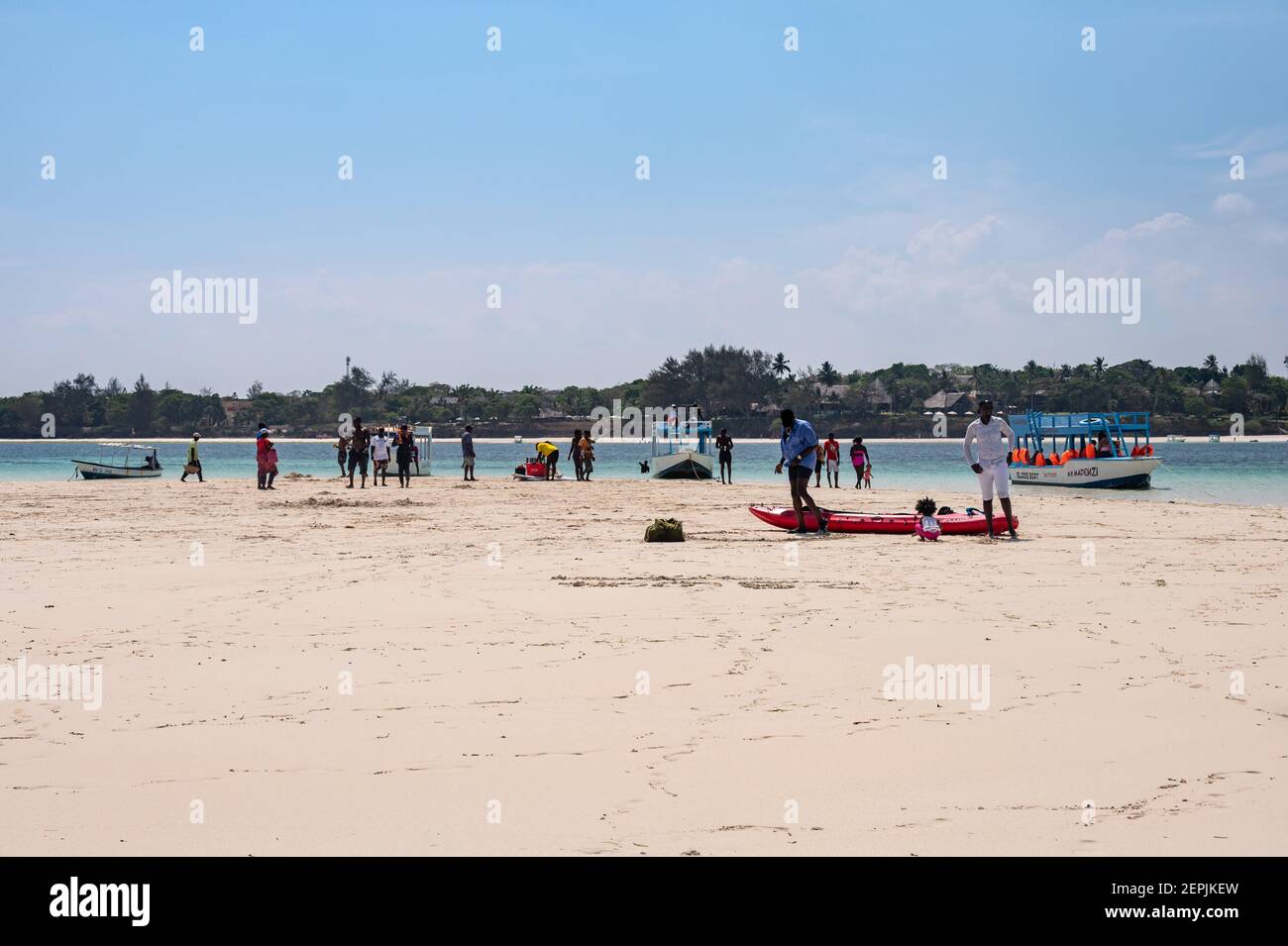 Ein Glasbodenboot, das von einer Ebbe-Sandbank mit Menschen auf dem Sand, Diani, Kenia, vertäut ist Stockfoto