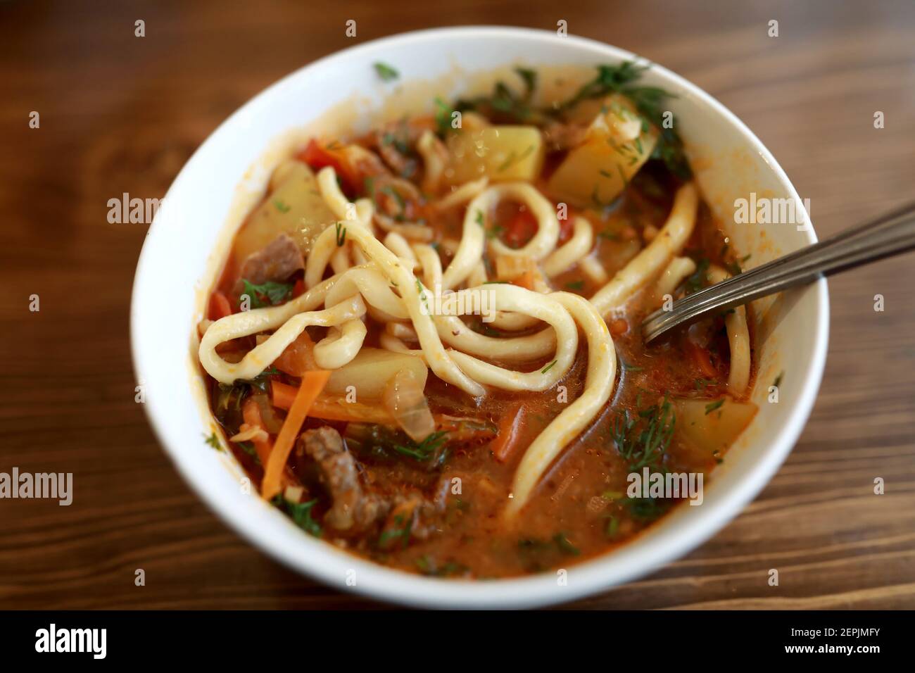 Schüssel mit Lagman-Suppe auf Holztisch im Restaurant Stockfoto