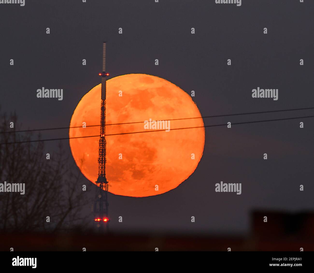 Wimbledon, London, Großbritannien. 27. Februar 2021. Der Vollschnee-Mond steigt hinter dem 219 Meter hohen Sender-Turm Crystal Palace auf. Quelle: Malcolm Park/Alamy Live News Stockfoto