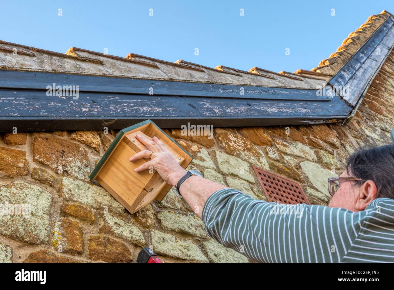 Frau Befestigung Vogelnistkasten unter Dachrinnen. Stockfoto