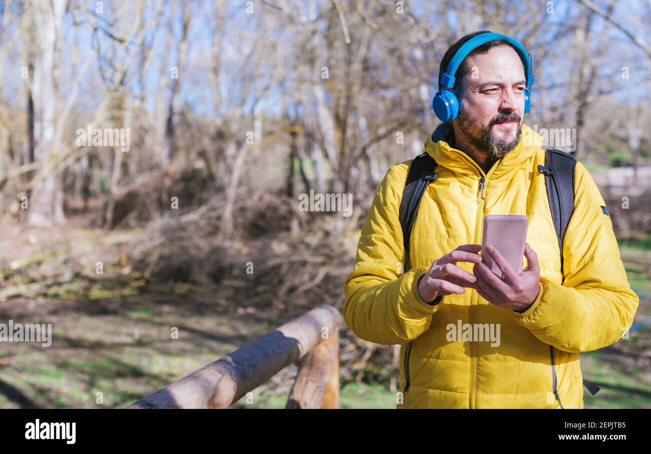 Hipster Mann mit einem Bart Musik hören mit Kopfhörer und Handy, während zu Fuß an einem sonnigen Tag. Stockfoto