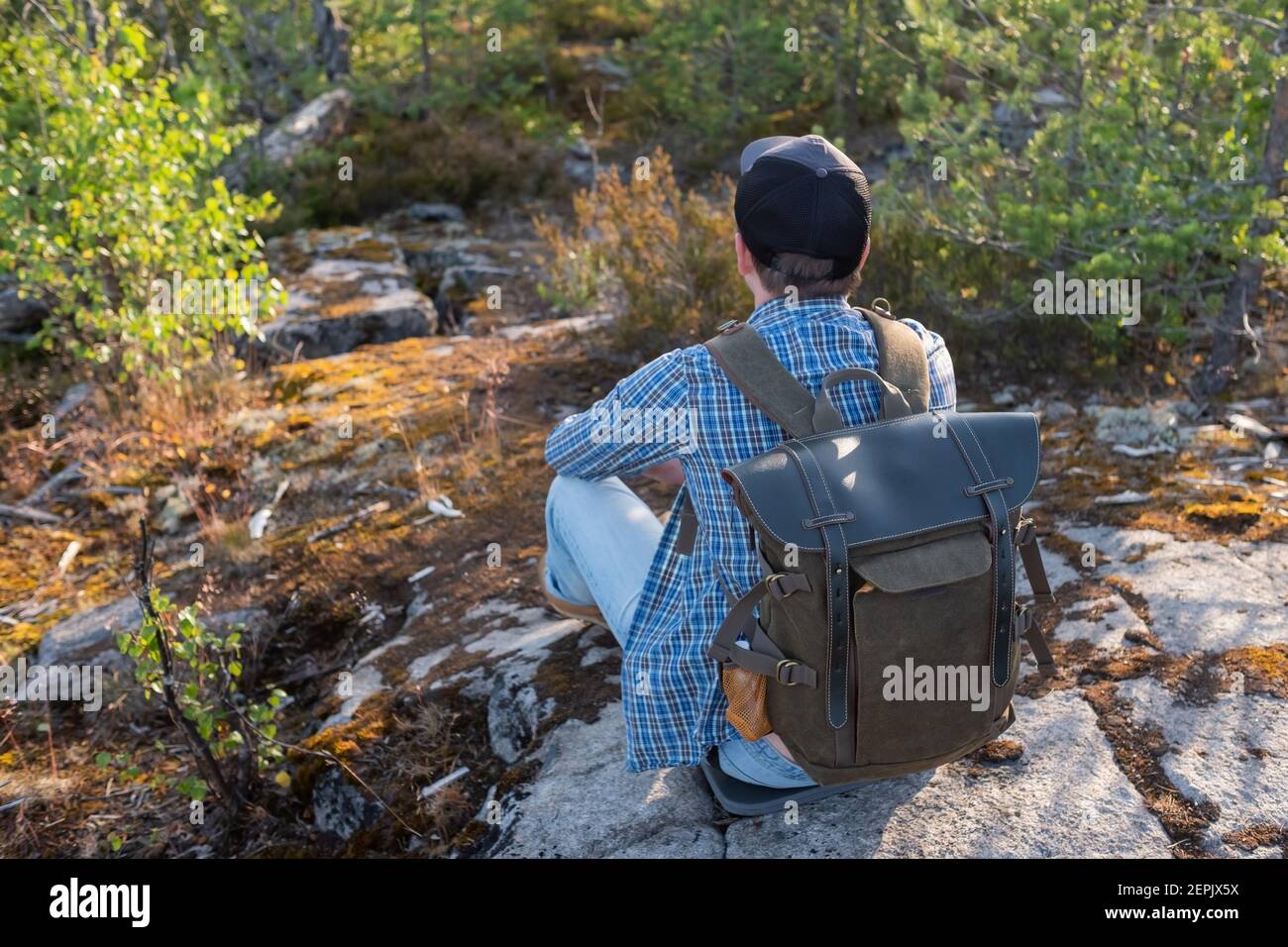 Junger Mann steht allein draußen mit wilden Wald auf dem Hintergrund. Travel Lifestyle Concept Rückansicht Stockfoto