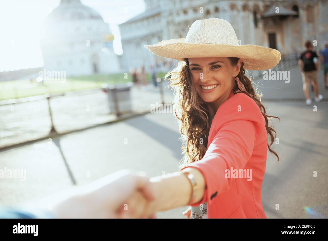 Lächelnd trendige Solo-Tourist Frau in Blumenkleid mit Hut erkunden Sehenswürdigkeiten mit Freund in der Nähe von Duomo di Pisa. Stockfoto