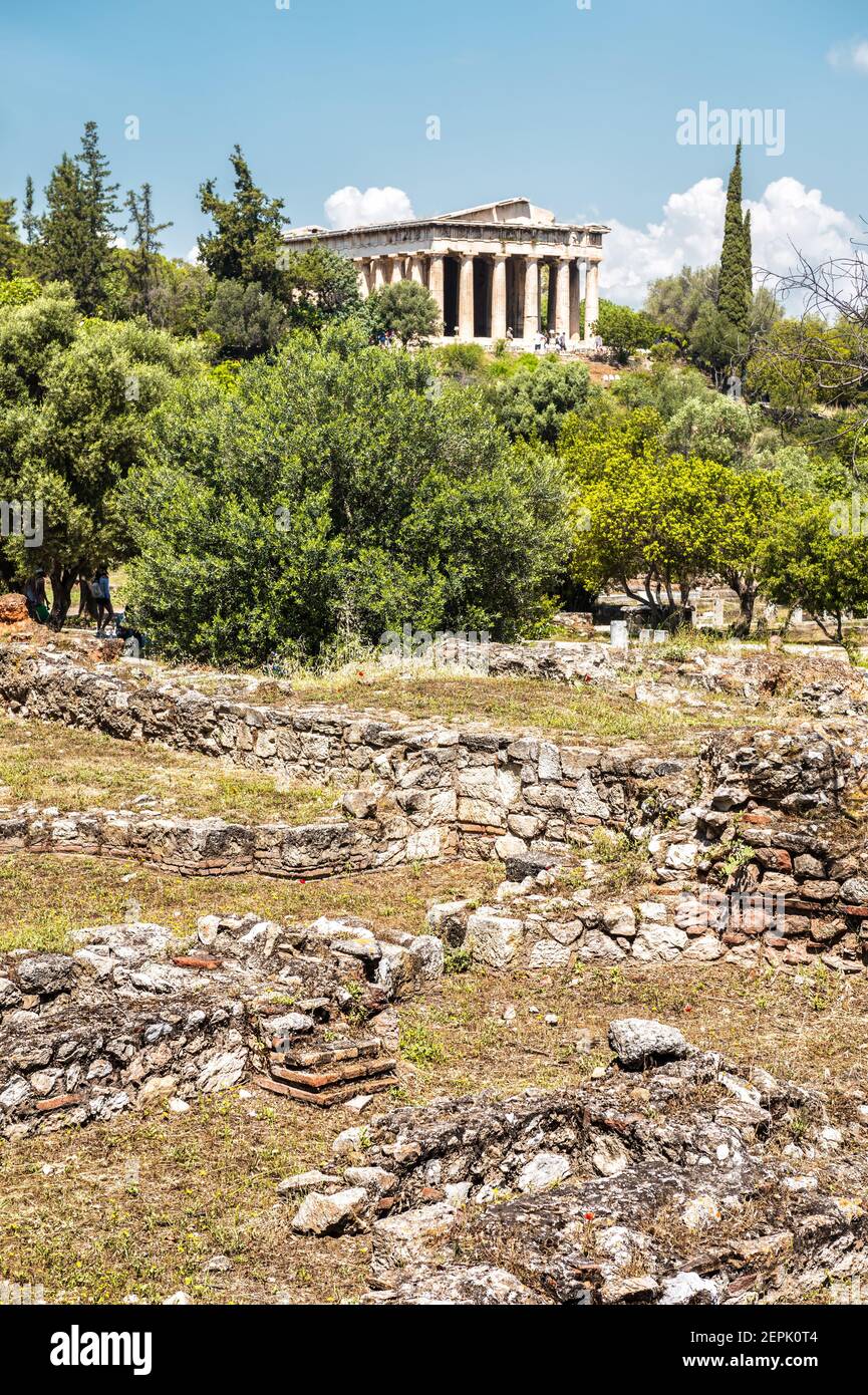 Antike griechische Ruinen in Agora, Athen, Griechenland. Tempel des Hephaestus, Wahrzeichen von Athen in der Ferne. Vertikale landschaftliche Ansicht der Überreste der berühmten classica Stockfoto