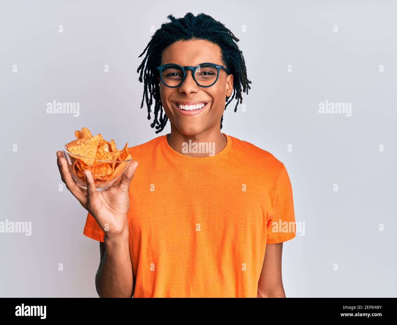 Junger afroamerikanischer Mann hält Nachos Kartoffelchips, die positiv ...