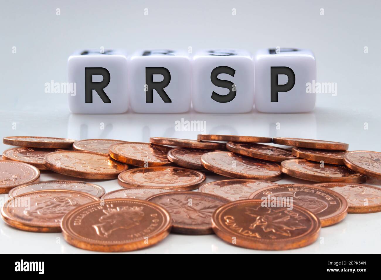 RRSP Buchstaben auf weißen Blöcken mit Münzen auf einem klaren Hintergrund Stockfoto