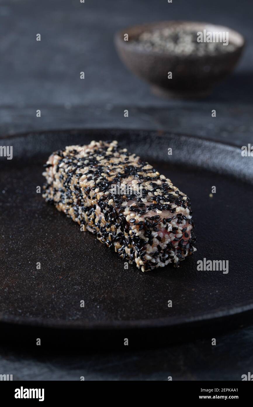 Gebratenes Thunfischsteak in schwarzem Sesam mit Spargel auf Schwarz Platte Stockfoto