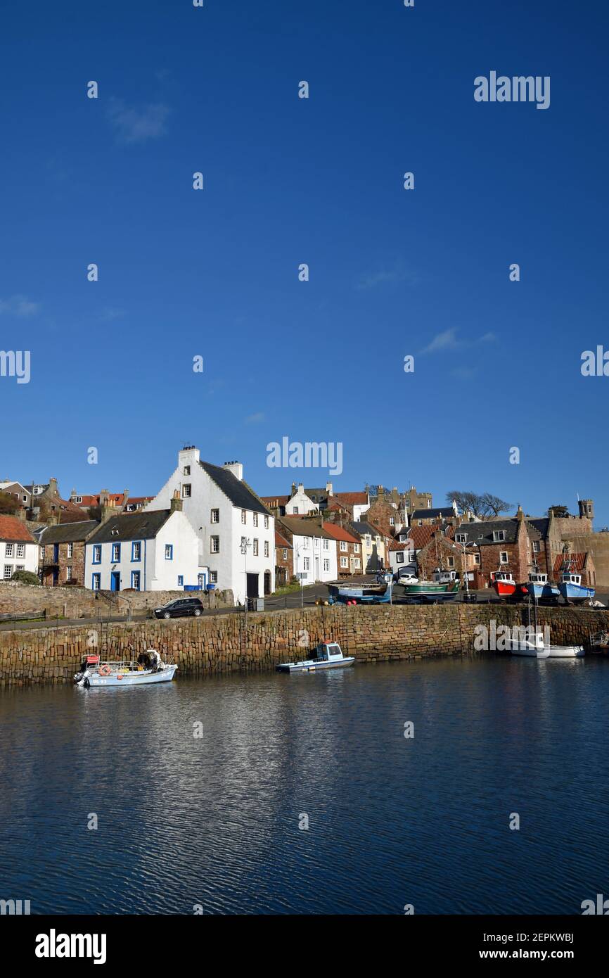 Crail Harbour in East Neuk of Fife, Schottland an einem sonnigen Tag mit Booten, Hafenmauer, traditionellen Häusern. Blauer Himmel und leichte Wolke. Stockfoto