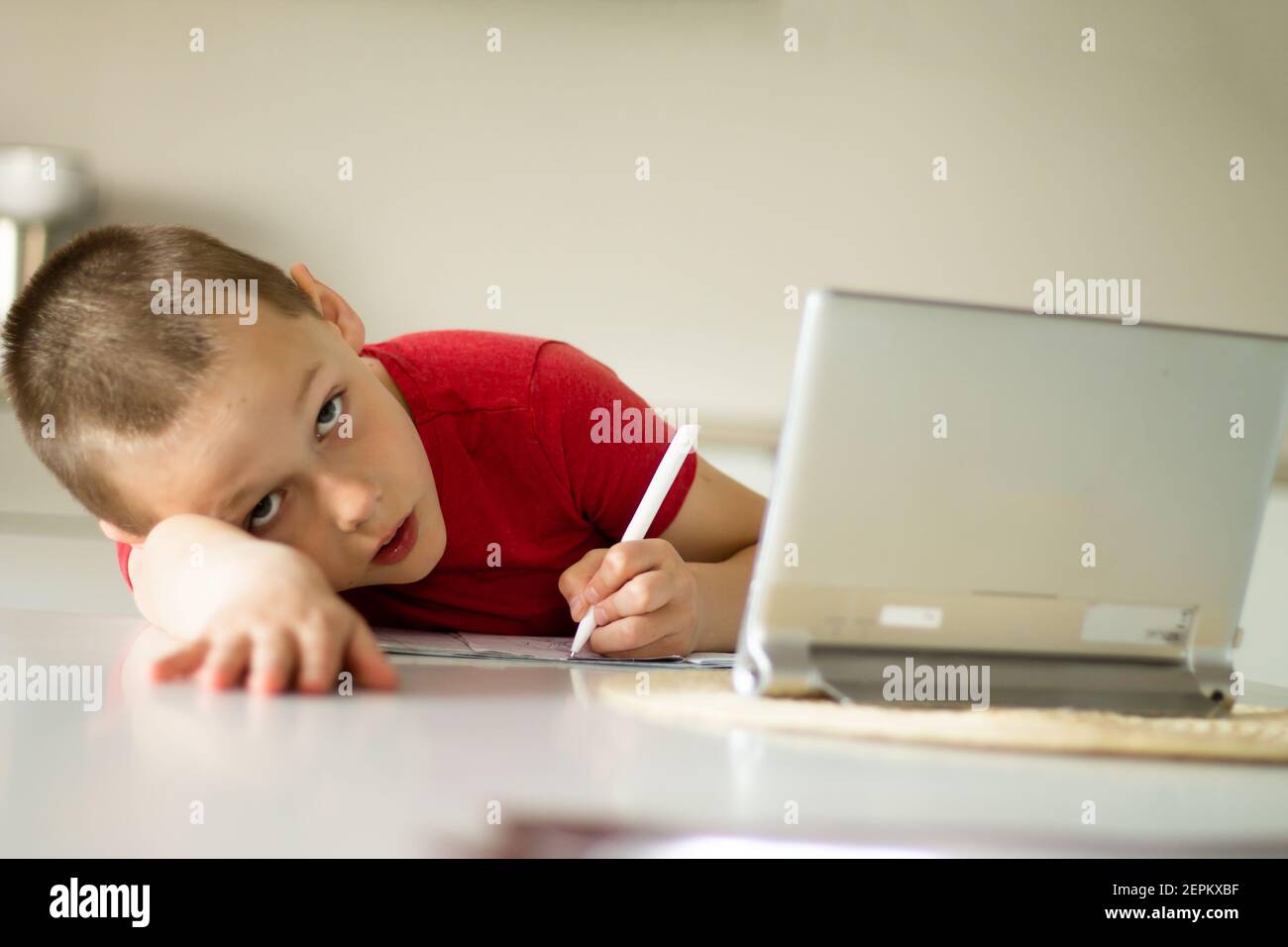 Müde Junge 6-10 schließt Schulunterricht und Hausaufgaben online in der Küche, Blick auf den Tablet-Computer. Das Konzept der Fernbildung. Bleiben Sie bei Stockfoto