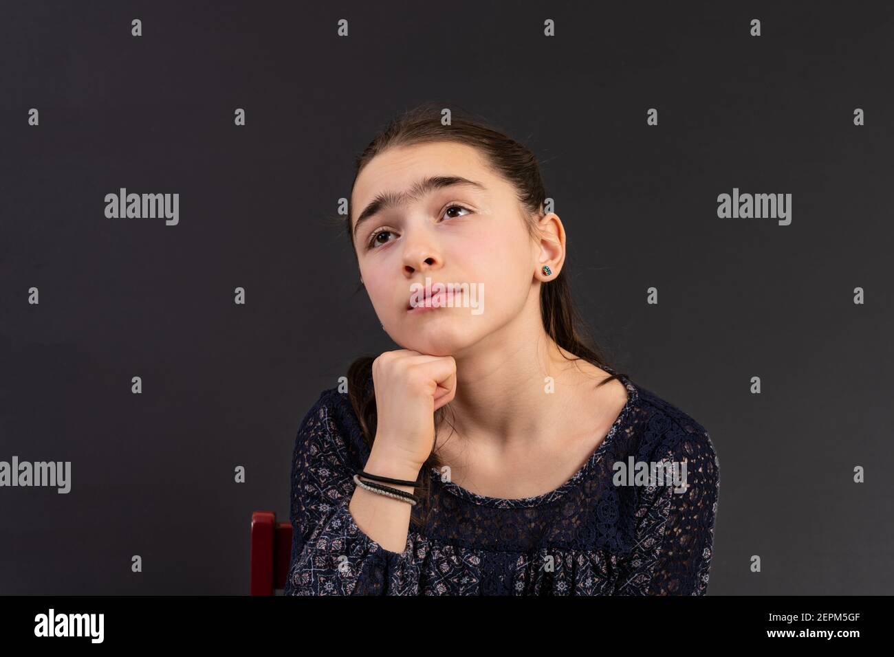 Portrait von jungen Mädchen suchen isoliert vor einem Kreidetafel Hintergrund. Stimmung Gefühle Persönlichkeit und Gesichtsausdruck Konzept. Stockfoto