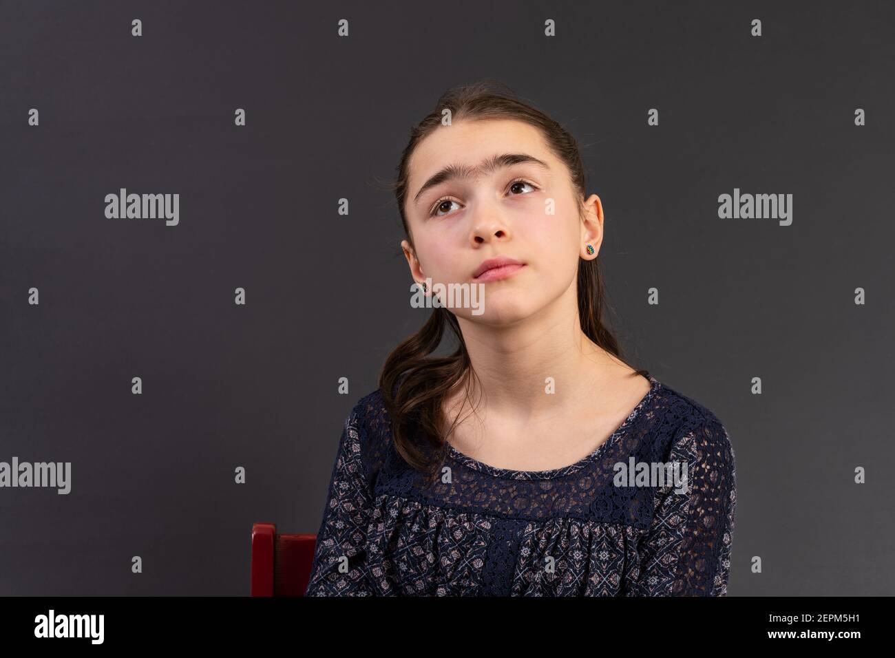 Portrait von jungen Mädchen suchen isoliert vor einem Kreidetafel Hintergrund. Stimmung Gefühle Persönlichkeit und Gesichtsausdruck Konzept. Stockfoto