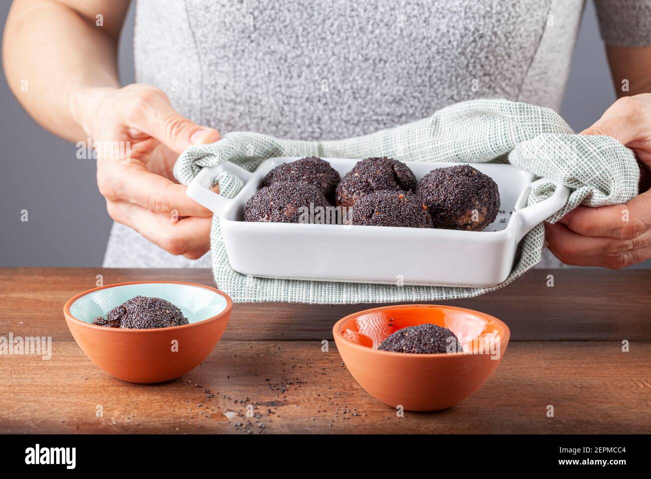 Eine Frau trägt eine heiße Schale mit Mohnsamen bedeckt Kuchenbällchen ...