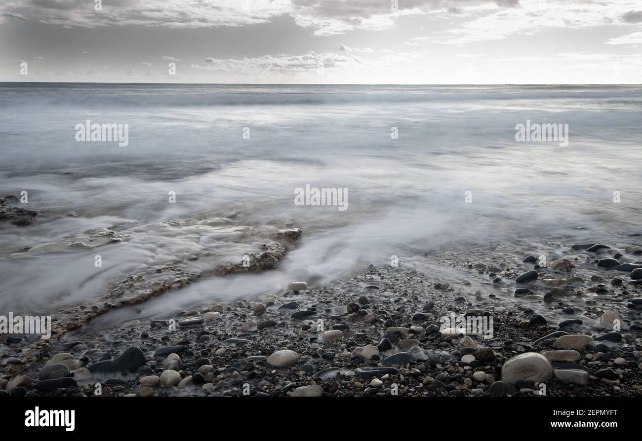 Seeschiffe planschen mit Steinen an die Küste gegen den stürmischen dramatischen Wolkenhimmel. Winterzeit, Limassol zypern Stockfoto