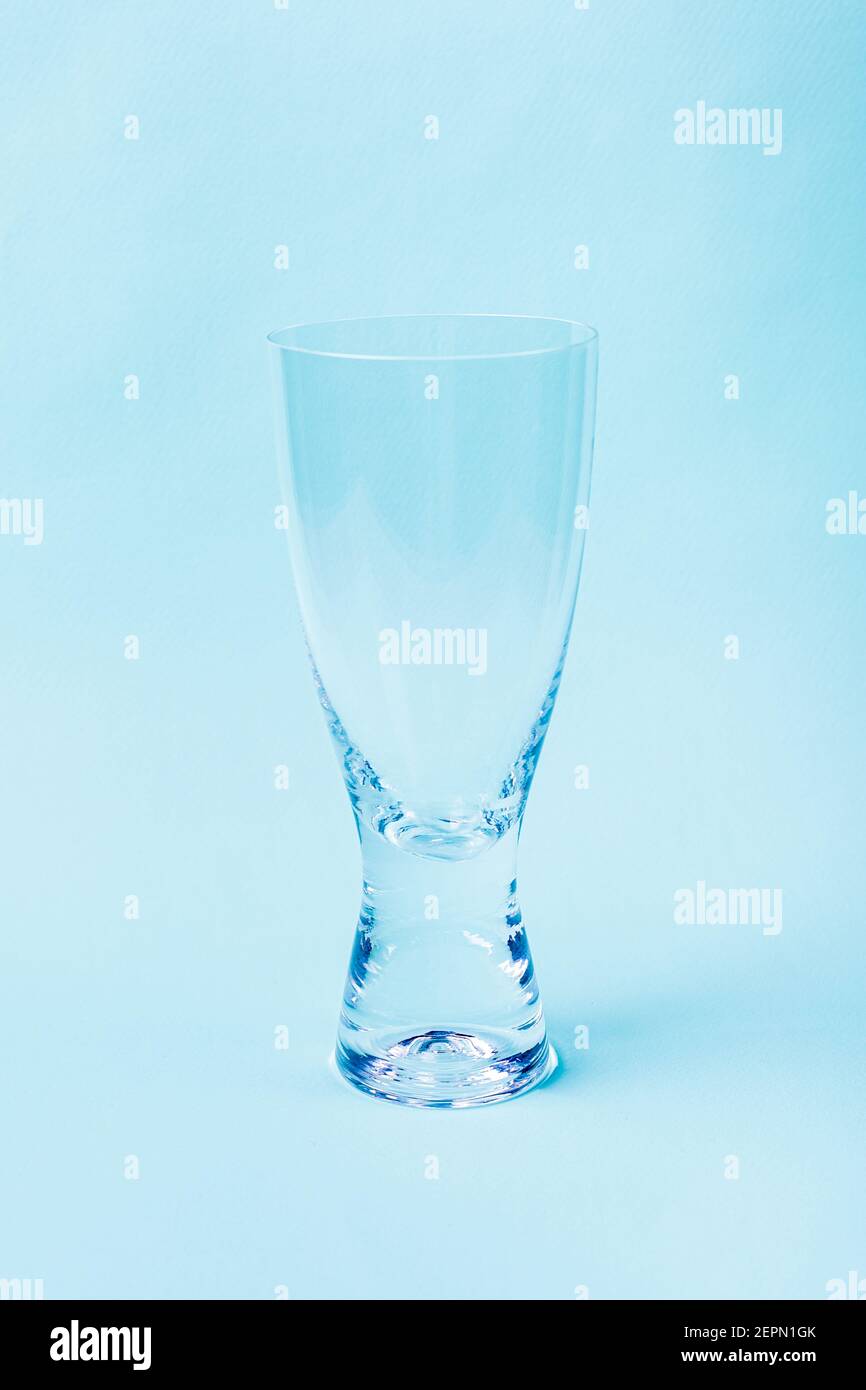 Leeres Glas aus transparentem Glas auf blauem Hintergrund. Zum Trinken, Durstlöschen, Küchenutensilien, Geschirr. Stockfoto