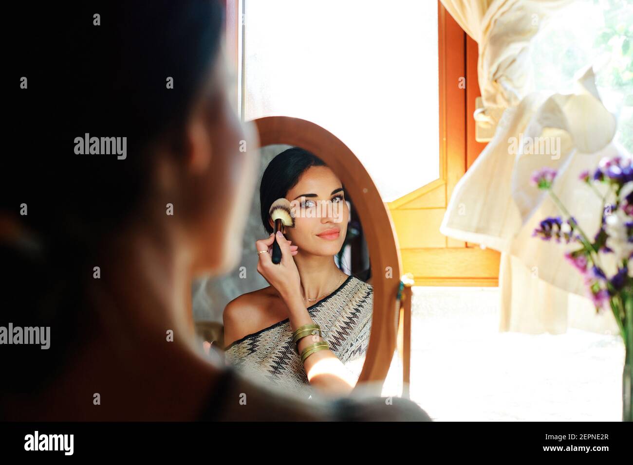 Rückansicht der Ernte junge zarte weibliche Anwendung Rouge mit Pinsel beim Blick in Spiegel zu Hause Stockfoto