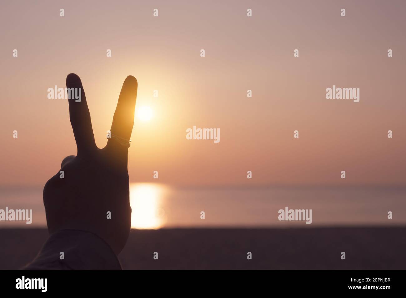 Frieden aus oder kämpfen Metapher zwei Finger Hand Zeichen vor einem Sonnenuntergang. Glückliche Menschen genießen die Natur. Stockfoto