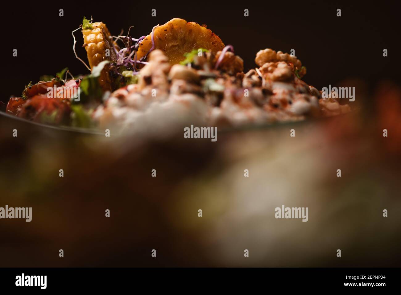 Schüssel mit leckeren Süßkartoffelscheiben mit Kirschtomaten in der Nähe Grüne Erbsen und Sesamsamen auf dunklem Grund Stockfoto