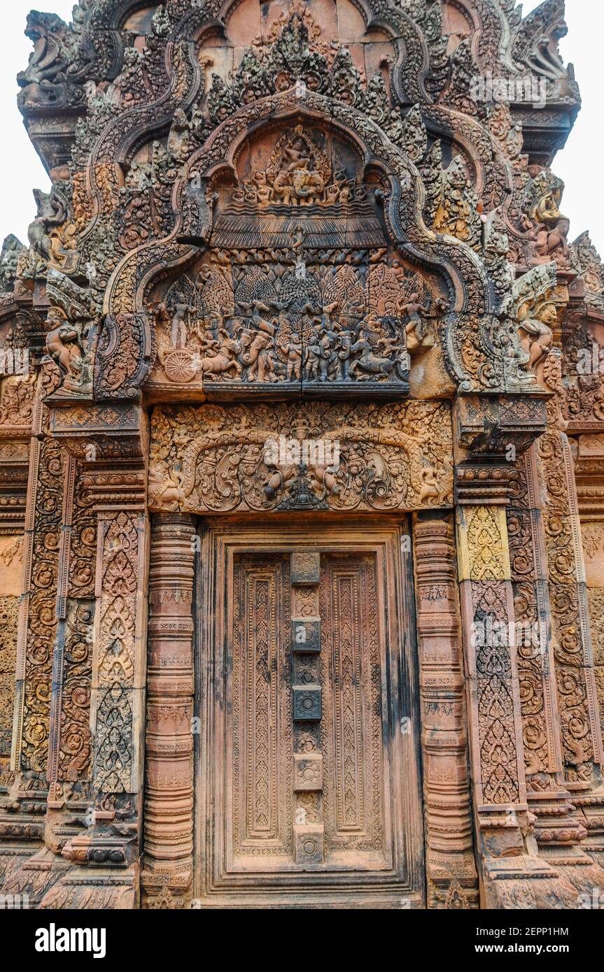 Die Gebäude im Tempel des Banteay Srei aus dem 10th. Jahrhundert sind mit kunstvoll geschnitzten Darstellungen des hinduistischen Ramayana-Epos in rosa Sandstein bedeckt. Stockfoto
