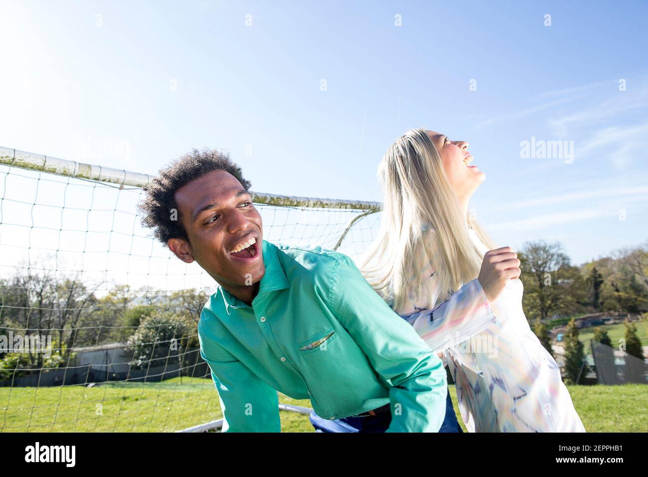 Fußball-Fashion-Geschichte mit einem schwarzen männlichen Modell und Blondine Chinesische weibliche Modell erzielte ein Tor auf einem Fußballplatz Stockfoto