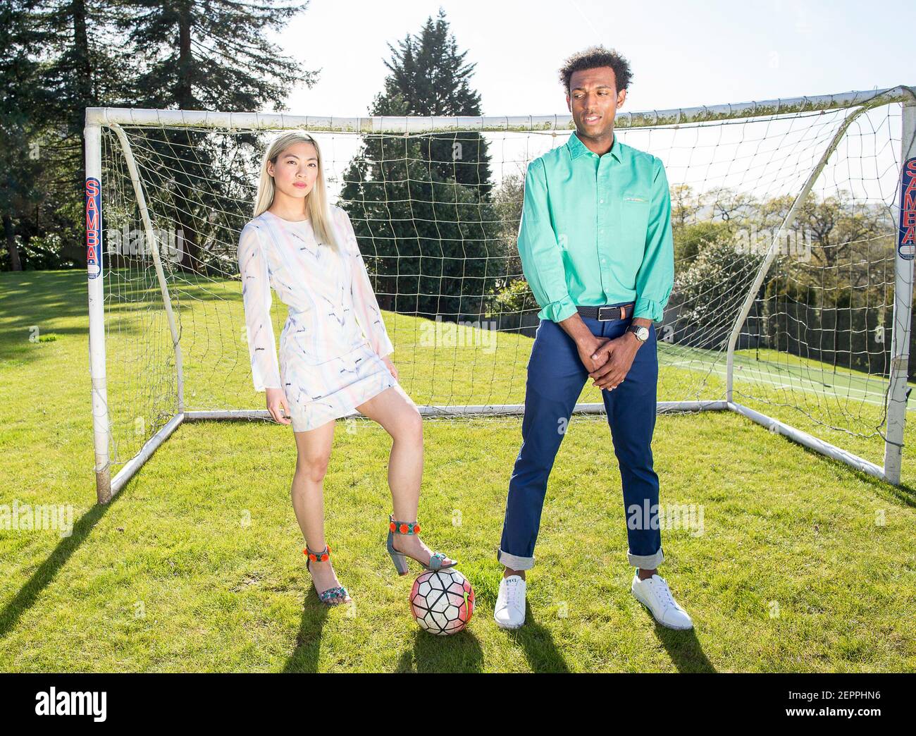 Fußball-Fashion-Geschichte mit einem schwarzen männlichen Modell und Blondine Chinesische weibliche Modell erzielte ein Tor auf einem Fußballplatz Stockfoto