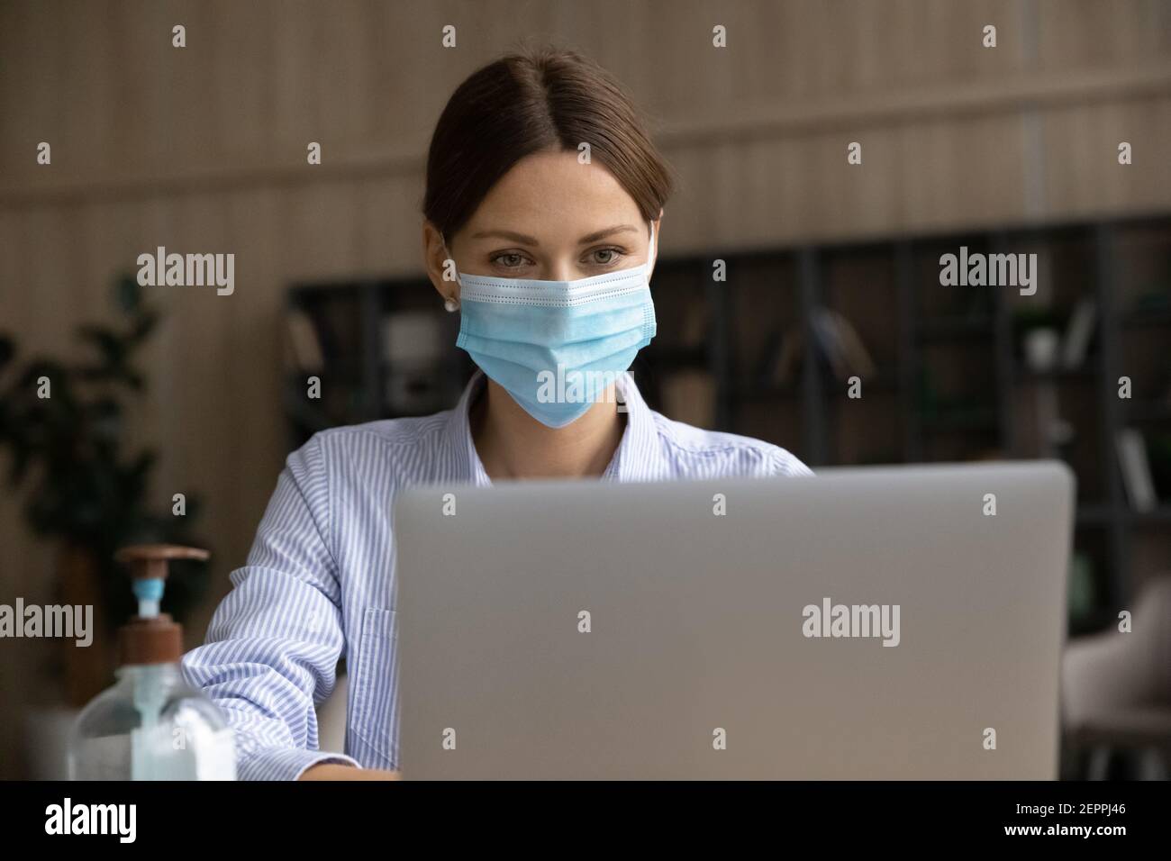 Geschäftsfrau in Facemask Arbeit auf Laptop online Stockfoto
