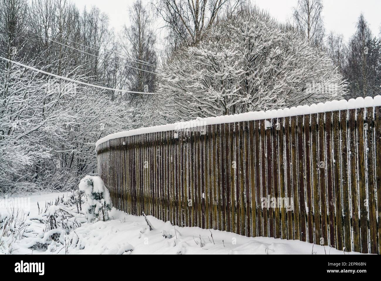 Holzzaun mit Schneekappen im Winter. Stockfoto