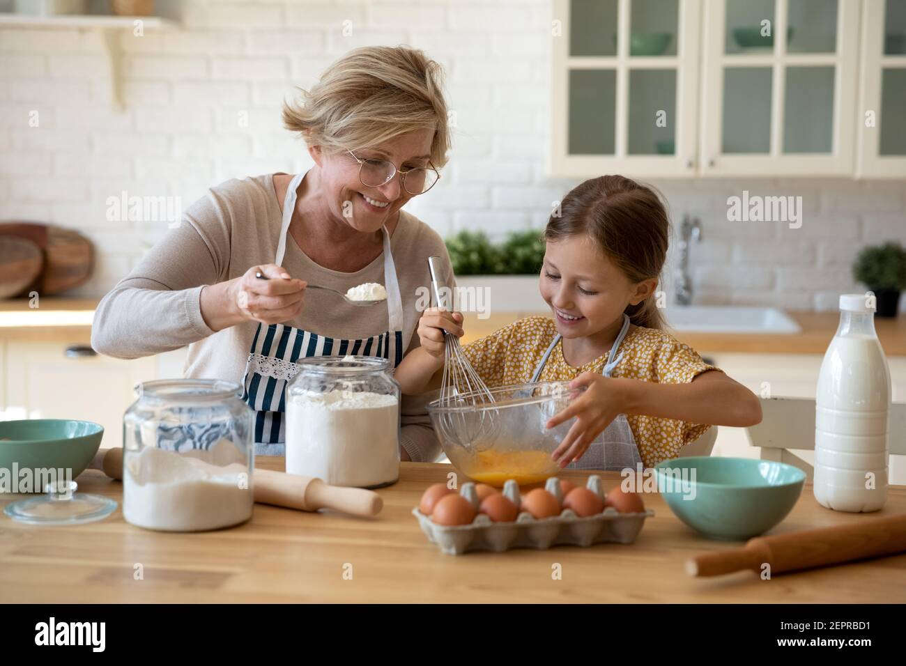 Glücklich kleines Mädchen Hilfe Senior Oma bei Küche mischen Teig Stockfoto