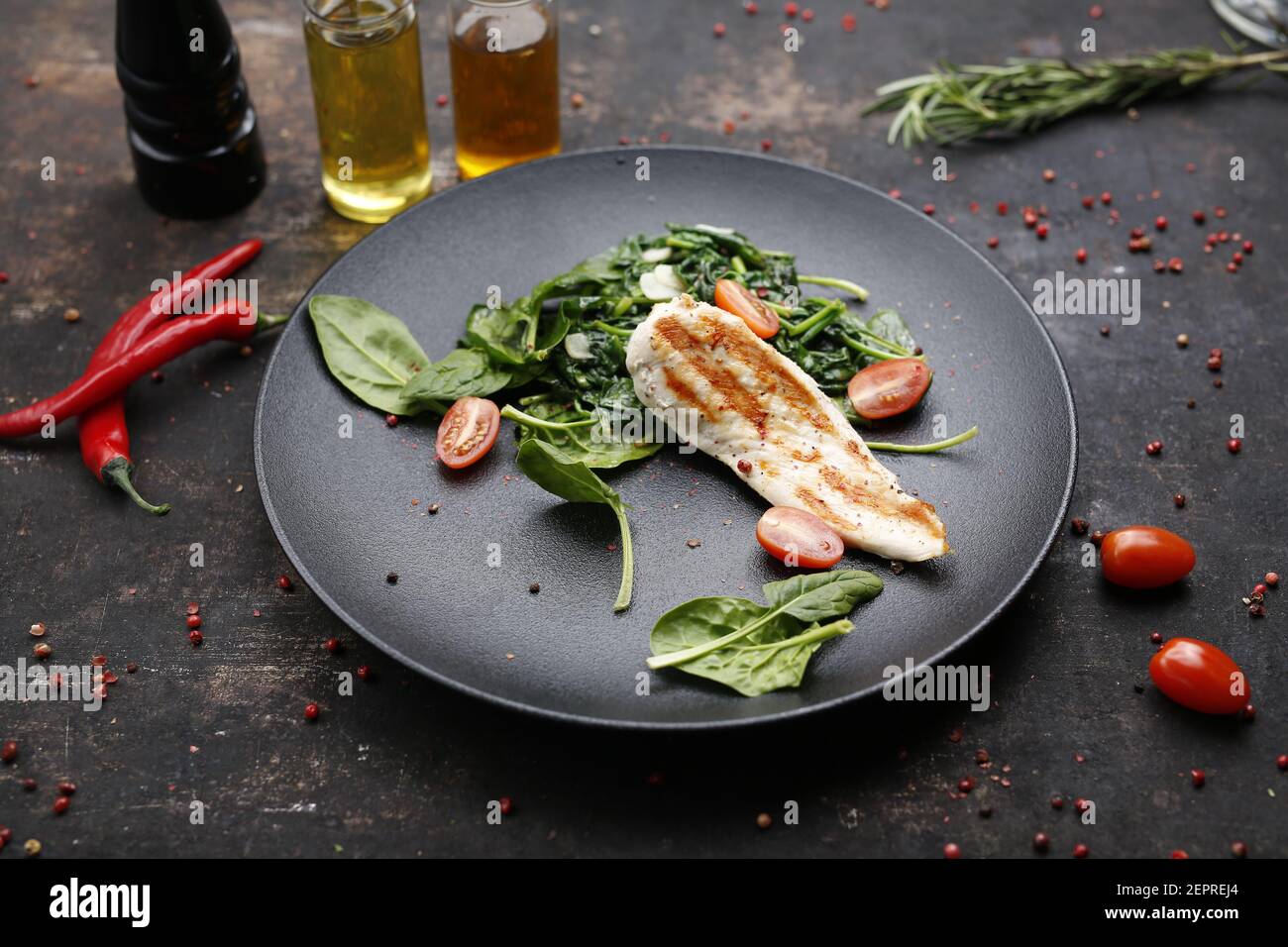 Gegrilltes Hähnchenfilet auf Spinat, diätetisches Essen. Das fertige Gericht auf einem Teller serviert. Serviervorschlag, kulinarische Fotografie. Stockfoto