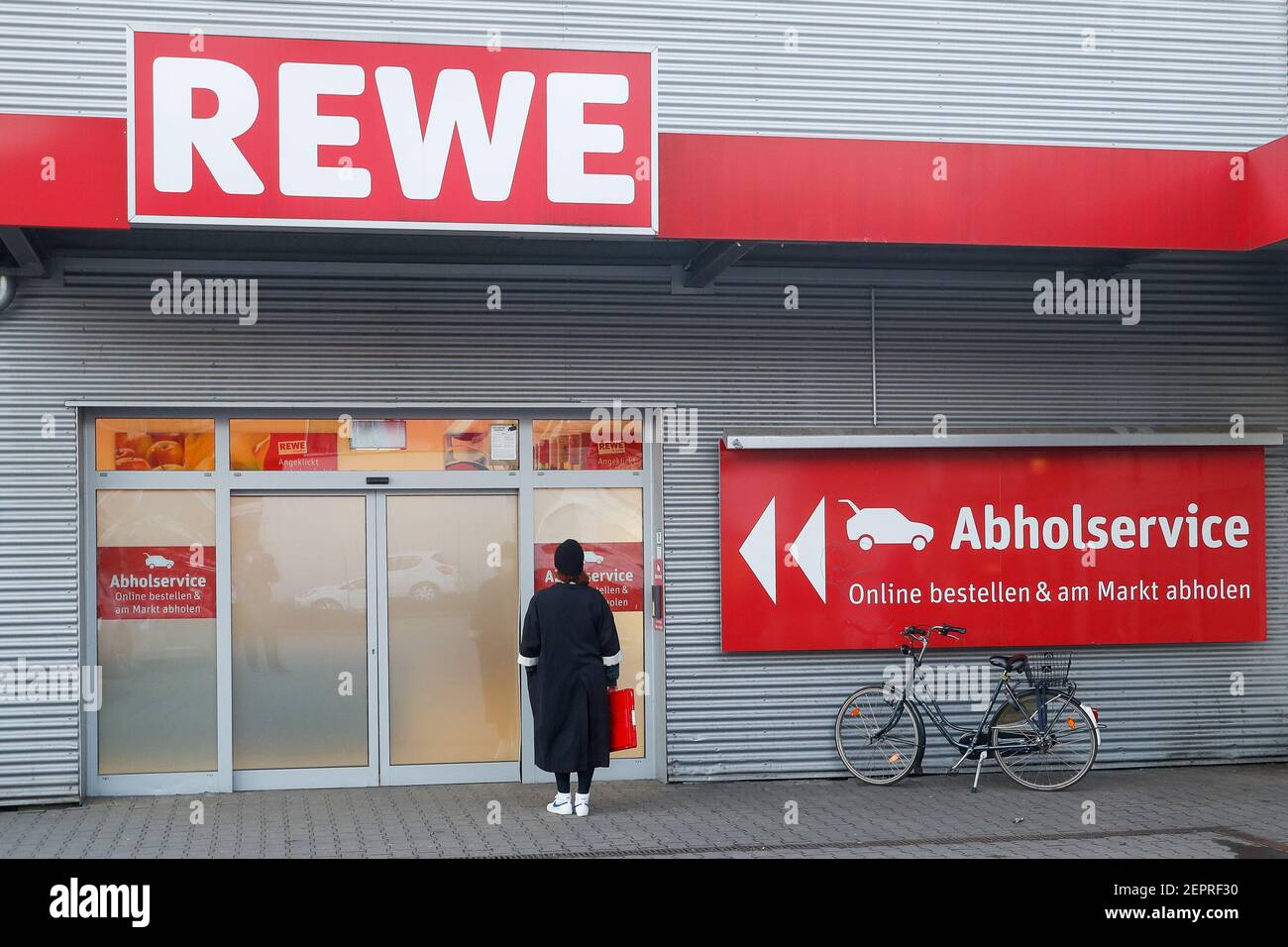 Berlin, Deutschland. Februar 2021, 27th. Vor dem Eingang des REWE-Abholdienstes steht eine Frau. Quelle: Gerald Matzka/dpa-Zentralbild/ZB/dpa/Alamy Live News Stockfoto