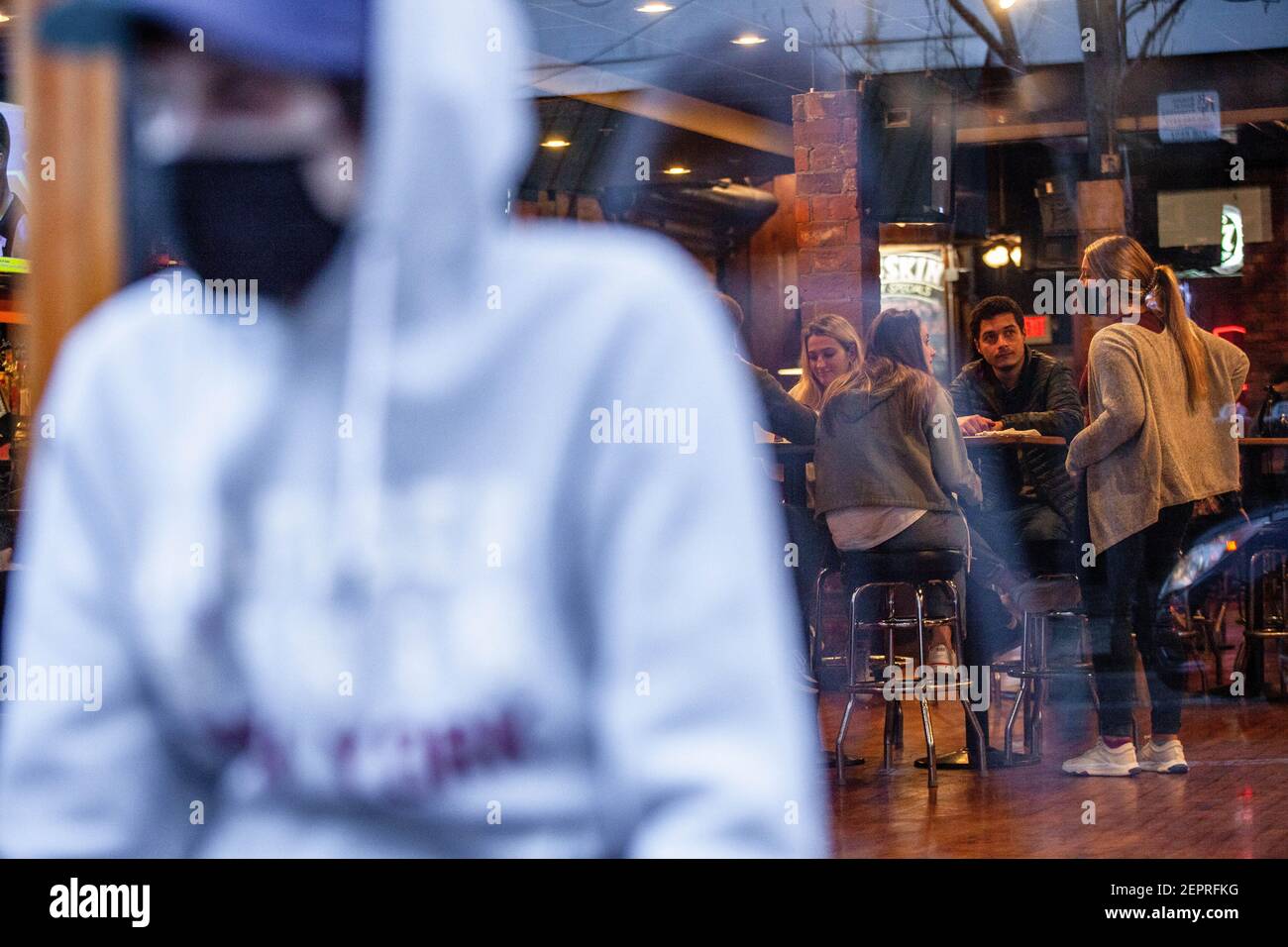 Athen, Usa. Februar 2021, 27th. Gavin Lloyd, 24, aus Athen, Ohio wartet auf die Gelegenheit, die Pigskin Bar and Grille zu betreten. Während das Wetter in Ohio aufwärmt Studenten von der Ohio University Kopf zur Court Street, um an Bars zu sozialisieren. Die Impfstoffverteilung ist in Ohio noch im Gange, aber für Studenten, die nicht mit vielen Personen außerhalb ihrer Kohorte interagieren, hat die Bedrohung durch die Coronavirus-Krankheit (COVID-19) sie nicht davon abgehalten, eine Nacht in der Stadt zu verbringen. Kredit: SOPA Images Limited/Alamy Live Nachrichten Stockfoto