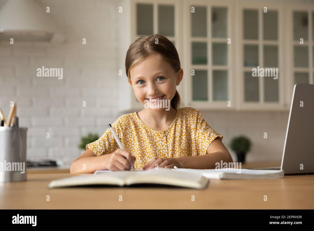 Portrait von kleinen Mädchen Schüler sitzen am Tisch schreiben Übungen Stockfoto