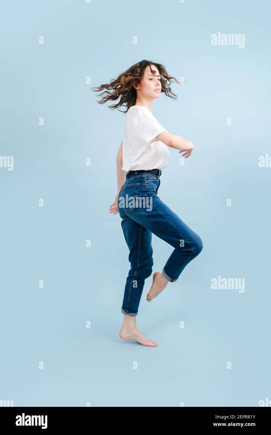 Dynamische zeitgenössische Tänzerin posiert vor blauem Studiohintergrund. Sie beugt sich mit dem gerade gebogenen Knöchel wie ein Pferd. In einem Körper rotierenden motio Stockfoto