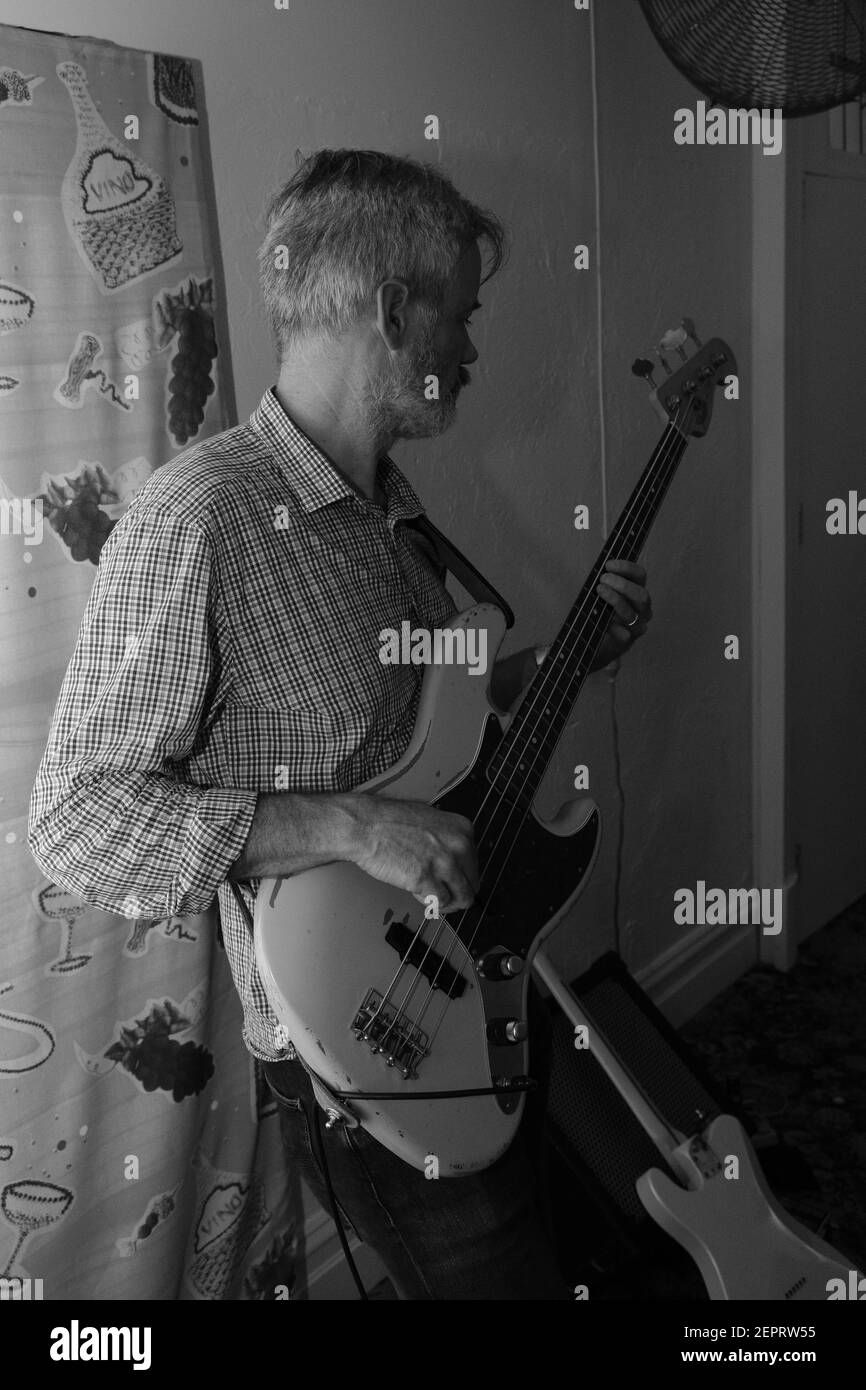 Ein Mann spielt eine Fender Jazz Bass Gitarre in einem Musikproberaum Stockfoto