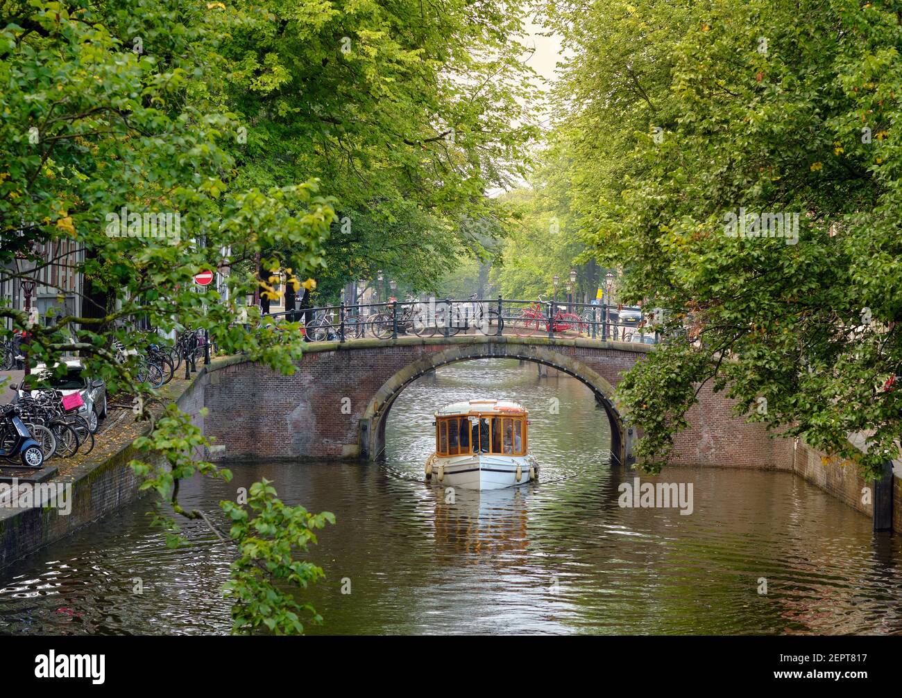 Eine kleine Vintage-Touristenbootfahrt / Tour durch die grünen Kanäle und Brücken von Amsterdam im Sommer - Niederlande, EU. Stockfoto