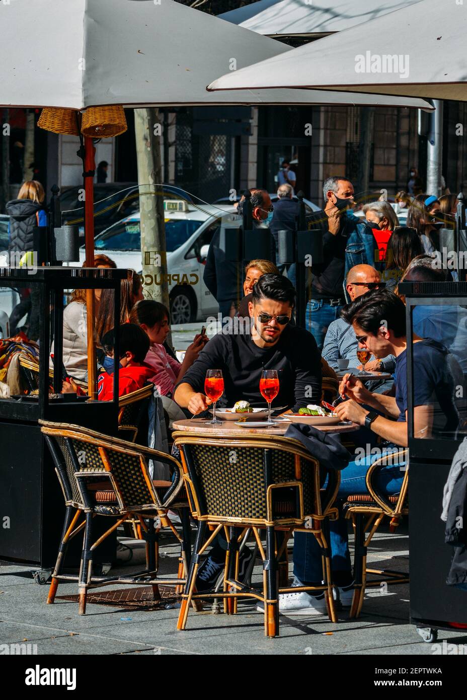 Madrid - Spanien - 28. Februar 2021: Die Menschen entspannen sich auf der Terrasse Café im beliebten Malasana-Viertel im Zentrum von Madrid, Spanien. Einige tragen Gesicht Mas Stockfoto
